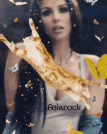 a woman is holding a cat that is flying through the air surrounded by butterflies and the word asiarock