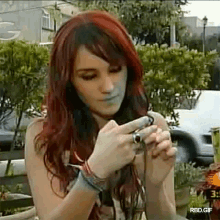 a woman with red hair is taking a picture with a cell phone .