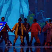 a group of people are dancing in front of a blue sign that says ' a ' on it