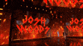 two men walking on a stage with josh written on the screen