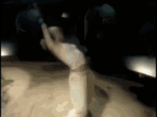 a woman in a white dress is dancing in a dark room