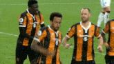 a group of soccer players wearing orange and black striped jerseys with the word sportpesa on the front