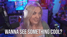 a woman wearing headphones is sitting in front of a microphone and saying `` wanna see something cool ? ''