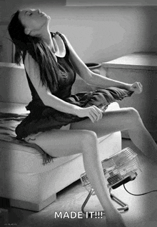 a black and white photo of a woman sitting in front of a fan with the caption made it !!