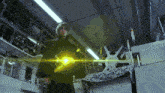a man in a black robe is standing in a room with a yellow light coming out of his hand
