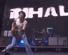 a man playing a guitar on stage in front of a sign that says ihal