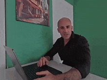 a man in a black shirt is using a laptop computer