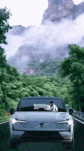 a white volvo car is driving down a road