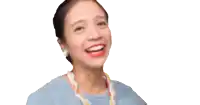 a woman wearing a blue shirt and a colorful necklace smiles for the camera
