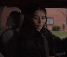 a woman is sitting in a car looking at her phone .