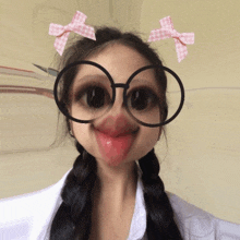 a girl with pigtails wearing glasses and a pink bow on her head