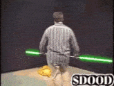 a man in a striped shirt is holding two green lightsabers and says sdood on the bottom right