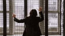 a woman in a suit behind bars with her hands on the bars