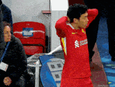 a soccer player wearing a red jersey that says standard chartered