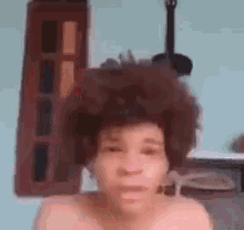 a man with a large afro is making a funny face in front of a building .