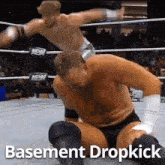 two men are wrestling in a ring with the words basement dropkick written below them .