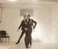 a couple of people dancing in a room with chairs