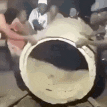 a group of people are standing around a large white drum .