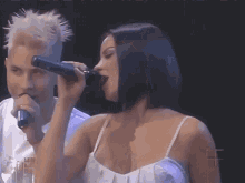 a woman singing into a microphone next to a man