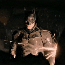 a close up of a man in a batman costume in the rain