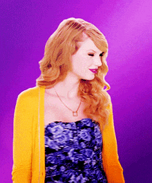 a woman wearing a yellow cardigan and a strapless blue dress
