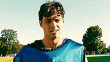 a man wearing a blue vest is standing on a soccer field .