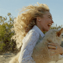 a woman in a white lace shirt is holding a cat