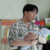a man in a plaid shirt is holding a baby .