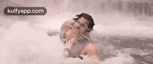 a man is swimming in a waterfall with a baby .