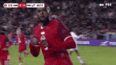 a man in a red jersey is running on a soccer field during a game