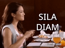 a woman sits at a table with a plate of food and a glass of orange juice and the words sila diam written on the bottom