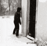 a black and white photo of a man standing in the snow .