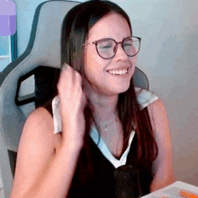 a woman wearing glasses is smiling while sitting in front of a microphone
