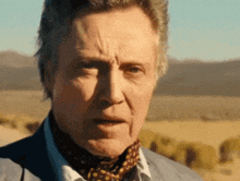 a man with a scarf around his neck is looking at the camera