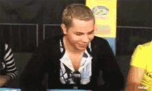 a man is sitting at a table with a sign that says rbd.gif on it