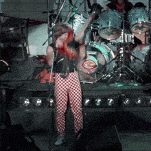 a man singing into a microphone in front of a drum set that has the word ludwig on it