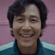 a close up of a man 's face smiling against a pink wall .