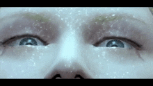 a close up of a person 's face with snow falling on it