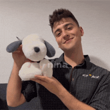 a man holding a stuffed snoopy dog with the word nina on his shirt