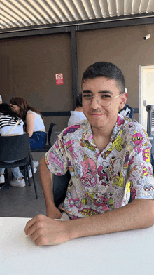 a man in a spongebob shirt sits at a table in front of a no smoking sign