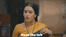a woman in a yellow saree is holding a book and saying haan tha toh