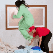 a man in a red hat is standing next to a woman in green pajamas who is jumping in the air