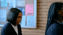 two girls are standing in front of a bulletin board with papers on it including one that says ' a ' on it