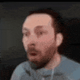 a blurry picture of a man with a beard and headphones making a surprised face .