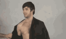 a man without a shirt is being touched by a person with a glass of wine in front of his face .