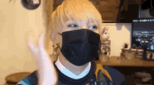 a man wearing a black face mask is standing in front of a tv