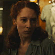 a woman with red hair is looking at the camera