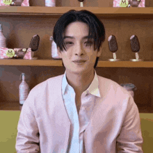 a man in a pink jacket is standing in front of a shelf with magnum ice cream on it