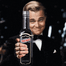 a man in a tuxedo is holding a bottle of marie sharp 's wine