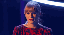 a close up of a woman 's face with a blue background and a red dress .